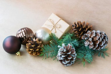 Noel oyuncaklar ve çam dalı ile hediye kutusu, koyu bej renkli arka plan üzerinde koni