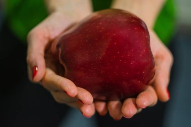 Kız elinde büyük kırmızı bir elma tutar.