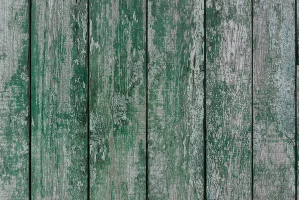 A photo of the rough wood planks texture painted in green long time ago