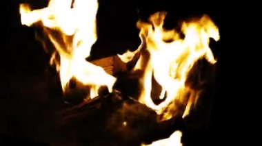 Kamp ateşindeki yakacak odunlardan çıkan alevlerin yavaş çekim videosu.