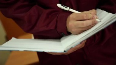 Şirket çalışanı girişleri büyük bir defterde beyaz tutamacı yapar. Çalışanın görünmez yüzüdür. O askıya bir defter tutar. Çalışanın kırmızı elbise çalışma.