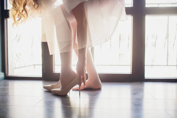 Braut zieht ihre Schuhe an. Details machen vor dem Hintergrund von Panoramafenstern den Unterschied — Stockfoto