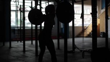 Hafif kahverengi saçlı siyah tozluk, pembe top ve spor ayakkabı giyen ve barbell, arka plan, çapraz eğitim egzersiz, portre, koyu spor salonu ile ağız kavgası yaparken uygun genç kız.