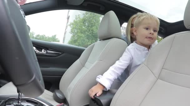 Ребенок сидит в салоне машины на заднем сидении. балуется подлокотником. Там горло игрушке — стоковое видео