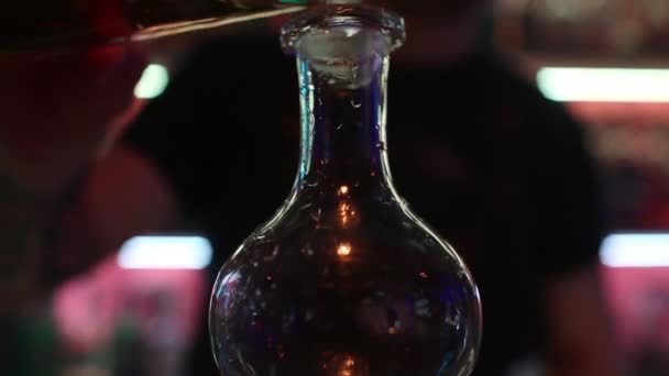 Expert barman is making cocktail at night club. Professional bartender at work in bar pouring sweet drink into glass on party at night club. Barman is decorating cocktail. — Stock Video