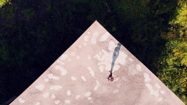 Ung kvinna gör yoga. taket till ett övergivet hus. Visa från ovan. bort från drönaren. — Stockvideo