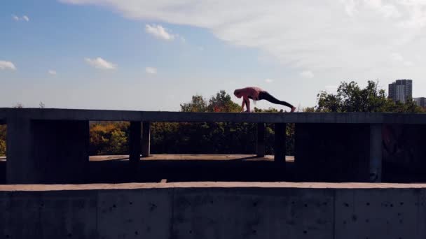 Ung kvinna gör yoga. taket till ett övergivet hus. Visa från ovan. bort från drönaren. — Stockvideo
