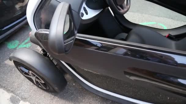 MONACO, MONAKO - 5 de julio de 2018: Micro-coche negro modelo Renault Twizy recarga en la calle de la ciudad enchufado con cable extensible . — Vídeos de Stock