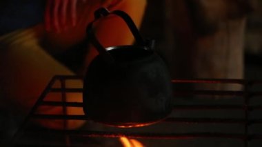 Çaydanlık kaynama alevler üzerinde ve ahşap günlükleri çölde geceleri yanma.