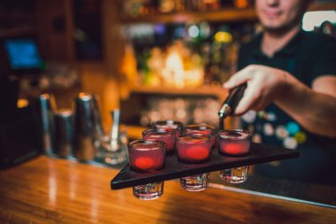 Barmen tekila çubuğunun arka planı cam içine yağıyor.