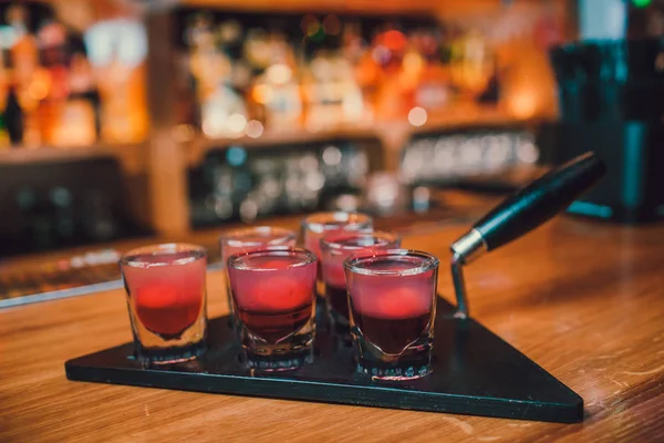 Barkeeper gießt Tequila ins Glas vor dem Hintergrund der Bar. — Stockfoto