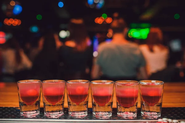 Barkeeper gießt Tequila ins Glas vor dem Hintergrund der Bar. — Stockfoto