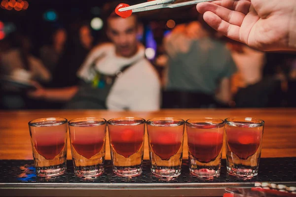 Cantinero está vertiendo tequila en vidrio sobre el fondo de la barra . — Foto de Stock