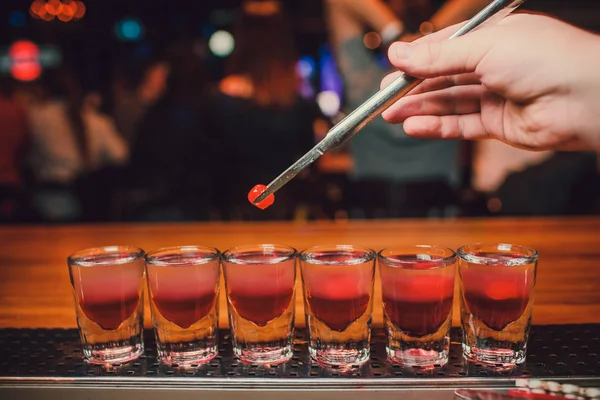 Barkeeper gießt Tequila ins Glas vor dem Hintergrund der Bar. — Stockfoto