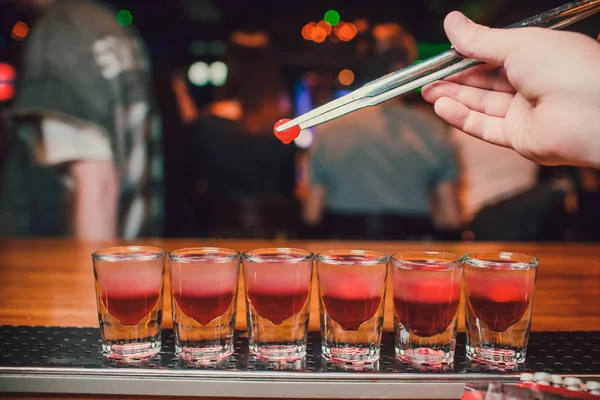 Barkeeper gießt Tequila ins Glas vor dem Hintergrund der Bar. — Stockfoto