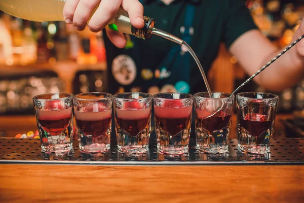 Bartender está derramando tequila em vidro contra o fundo do bar . — Fotografia de Stock