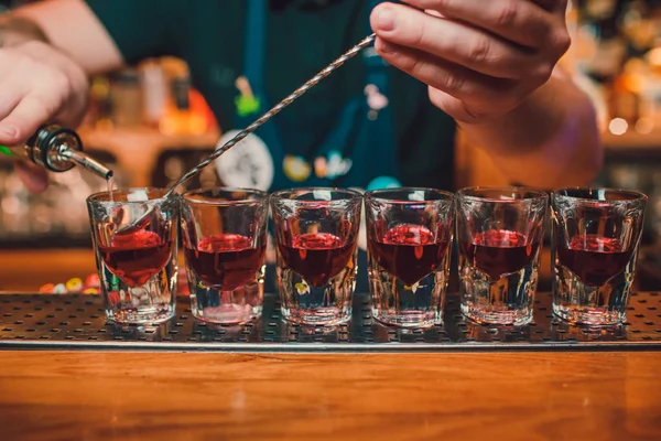 Бармен наливає текілу в склянку на тлі бару . — стокове фото