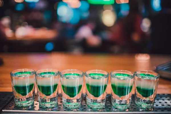 Líquido verde en vasos de chupito de pie sobre el mostrador . — Foto de Stock