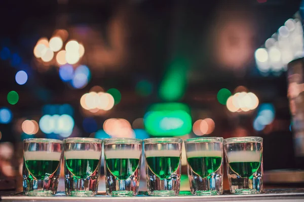 Líquido verde en vasos de chupito de pie sobre el mostrador . — Foto de Stock