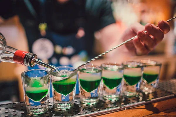 Líquido verde en vasos de chupito de pie sobre el mostrador. camarero preparando tiros — Foto de Stock