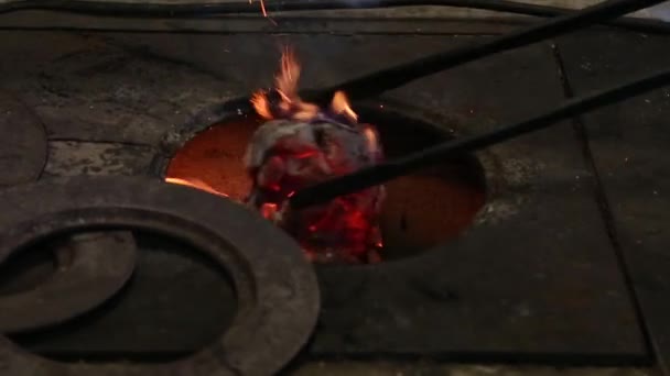 El herrero usa una vieja pala para avivar llamas dentro de la forja de carbón con el propósito de trabajar metal. . — Vídeos de Stock