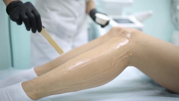 Beleza, depilação, depilação, depilação e conceito de pessoas - mulher bonita com aplicador aplicando cera depilatória em sua perna . — Vídeo de Stock