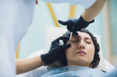 Güzellik uzmanı Doktor kadın müvekkili yüz güzelliği enjeksiyonları olun. Güzel yüz ve kozmetik eller şırınga ile. Gençleştirme ve hydratation. Klinik kozmetik kavramı.