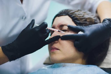 Güzellik uzmanı Doktor kadın müvekkili yüz güzelliği enjeksiyonları olun. Güzel yüz ve kozmetik eller şırınga ile. Gençleştirme ve hydratation. Klinik kozmetik kavramı.