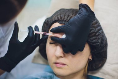 Güzellik uzmanı Doktor kadın müvekkili yüz güzelliği enjeksiyonları olun. Güzel yüz ve kozmetik eller şırınga ile. Gençleştirme ve hydratation. Klinik kozmetik kavramı.