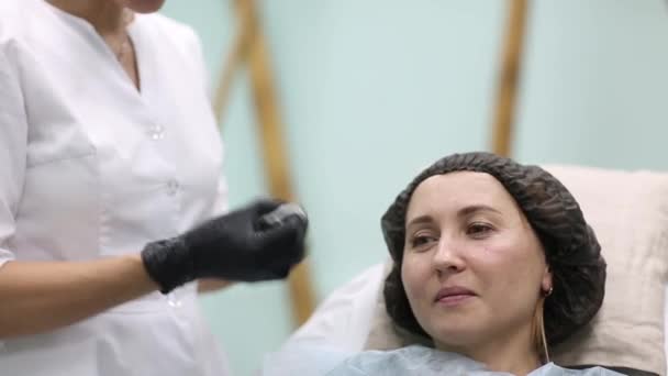 Kozmetikus orvos facial szépség injekciót, hogy neki nő ügyfél. Gyönyörű női arc és cosmetologists kezében a fecskendőt. Fiatalító és védőrétegét. A klinika kozmetológiai koncepció. — Stock videók