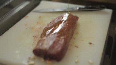 Lokanta mutfağı adlı gemide Dilimleme fileto mignon dostum. Şef yemek için taze et hazırlanıyor. Modern mutfağı backgroung sebze ve otlar ile