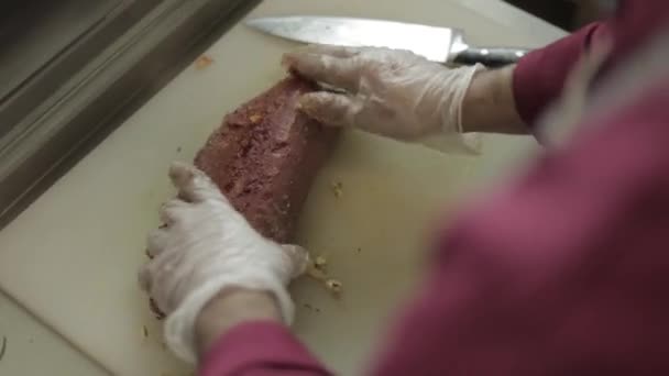 Mann schneidet Filet Mignon an Bord in der Restaurantküche. Koch bereitet frisches Fleisch zum Kochen zu. moderne Küche mit Kräutern und Gemüse