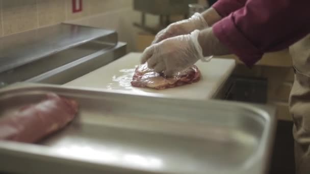 Hombre rebanando filete mignon a bordo en la cocina del restaurante. Chef preparando carne fresca para cocinar. Cocina moderna con fondo de hierbas y verduras — Vídeos de Stock