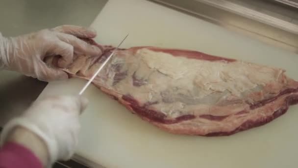 Hombre rebanando filete mignon a bordo en la cocina del restaurante. Chef preparando carne fresca para cocinar. Cocina moderna con fondo de hierbas y verduras — Vídeo de stock