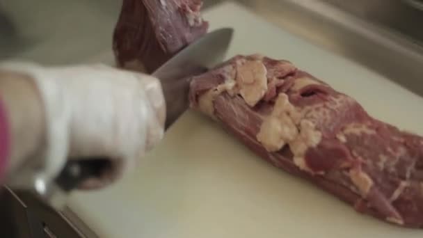 Mann schneidet Filet Mignon an Bord in der Restaurantküche. Koch bereitet frisches Fleisch zum Kochen zu. moderne Küche mit Kräutern und Gemüse — Stockvideo