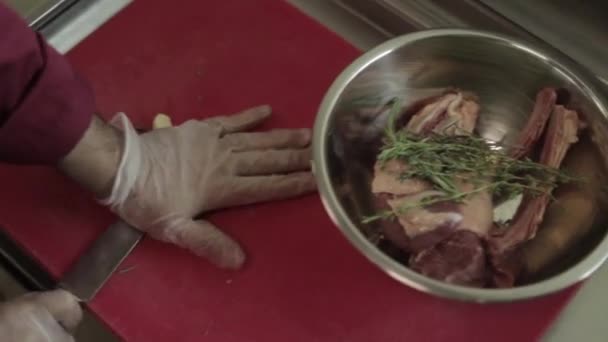 Человек режет филе миньон на борту в ресторане кухни. Шеф-повар готовит свежее мясо для приготовления. Современная кухня фоном с травами и овощами — стоковое видео