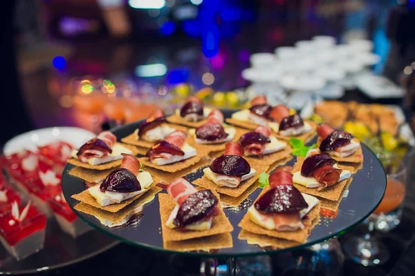 Mesa de banquete de catering bellamente decorada con hamburguesas, profiteroles, ensaladas y aperitivos fríos. Variedad de sabrosos aperitivos deliciosos en la mesa. —  Fotos de Stock