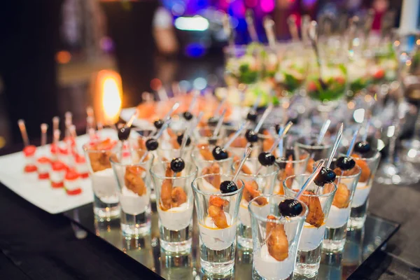 Beautifully decorated catering banquet table with burgers, profiteroles, salads and cold snacks. Variety of tasty delicious snacks on the table. — Stock Photo, Image