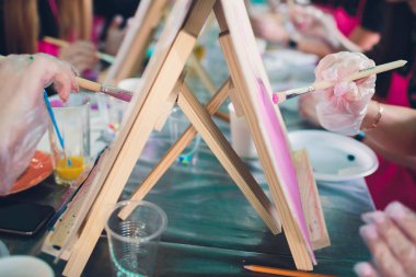 Sanatçı aksesuar koleksiyonu. Çadır bezi, bir tüp yağ boyası, sanat fırçaları, ahşap masada duran palet bıçağı. Sanatçı atölyesi arka planı.