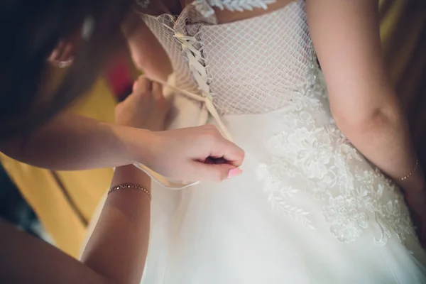 Družička vázání mašlí na elegantní svatební šaty nevěsty. — Stock fotografie