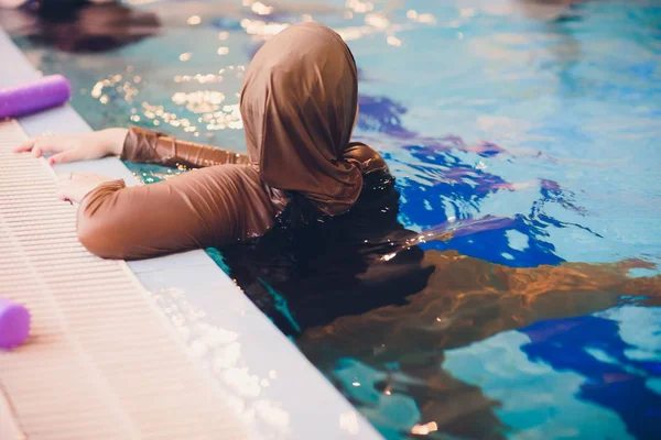 Muslimská dívka plavání na bazén hnědého oblečení. — Stock fotografie