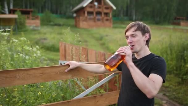 Close-up man bier drinken uit glas in openlucht in de buurt van het zwembad. Alcohol en vrije tijd concept. op de achtergrond van een houten huis — Stockvideo