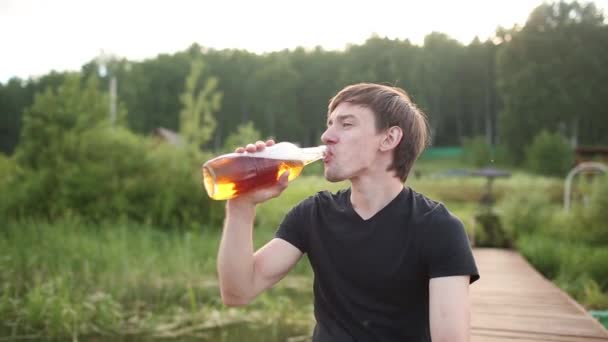 Un hombre cercano bebiendo cerveza de vidrio al aire libre cerca de la piscina. Concepto de alcohol y ocio . — Vídeo de stock