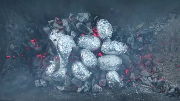 Крупный план костра с оранжевым и желтым пламенем и дровами и запечённой картошкой, покрытой алюминиевой фольгой, традиция празднования праздника Лаг Баомер еврейского костра обжарки картофеля в огне — стоковое видео