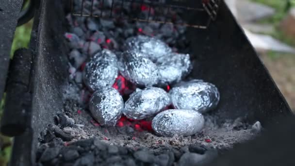 Primer plano de la hoguera con llamas naranjas y amarillas y leña y patatas al horno cubiertas con papel de aluminio, Lag Baomer fiesta judía celebración de la hoguera tradición de asar patatas en el fuego — Vídeos de Stock