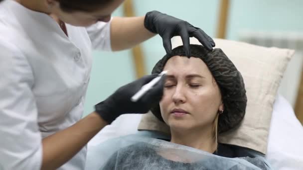 美容師は、医師は、彼女の女性のクライアントに顔美容注射を加えます。注射器の美しい女性の顔、cosmetologists 手。若返りと hydratation。美容クリニックのコンセプト. — ストック動画