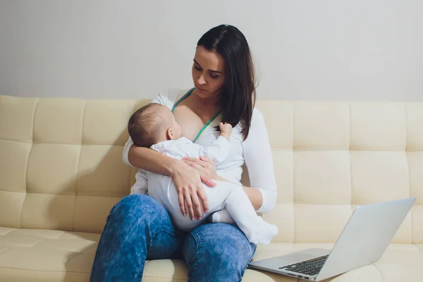 아름 다운 젊은 어머니는 노트북 컴퓨터 및 모유 수 유 신생아 아기 집에서 작업. 엄마-비즈니스 우먼. — 스톡 사진
