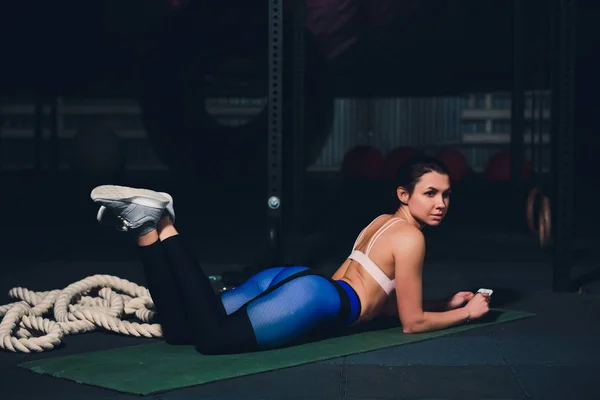 Ajuste mujer joven acostada en la esterilla de ejercicio haciendo ejercicios de estómago . —  Fotos de Stock