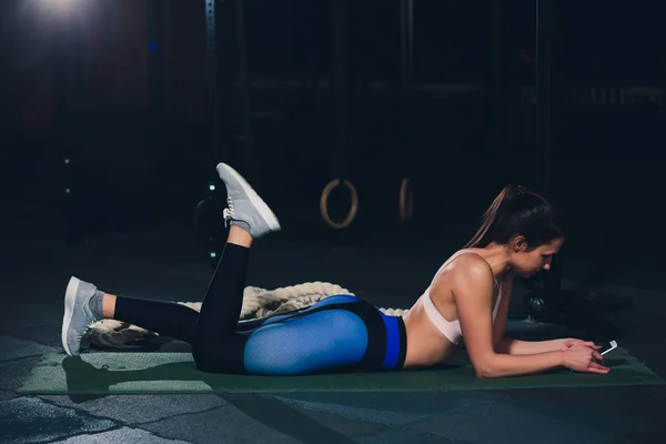 Adatto giovane donna sdraiata sul tappeto esercizio facendo esercizi di stomaco . — Foto Stock