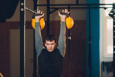 Genç adam kaldırma dumbbell ve kettlebell fitness Center.